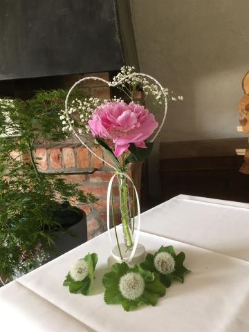 Blumenschmuck zur Hochzeit mit rosaner Rose in weißen Metallherz